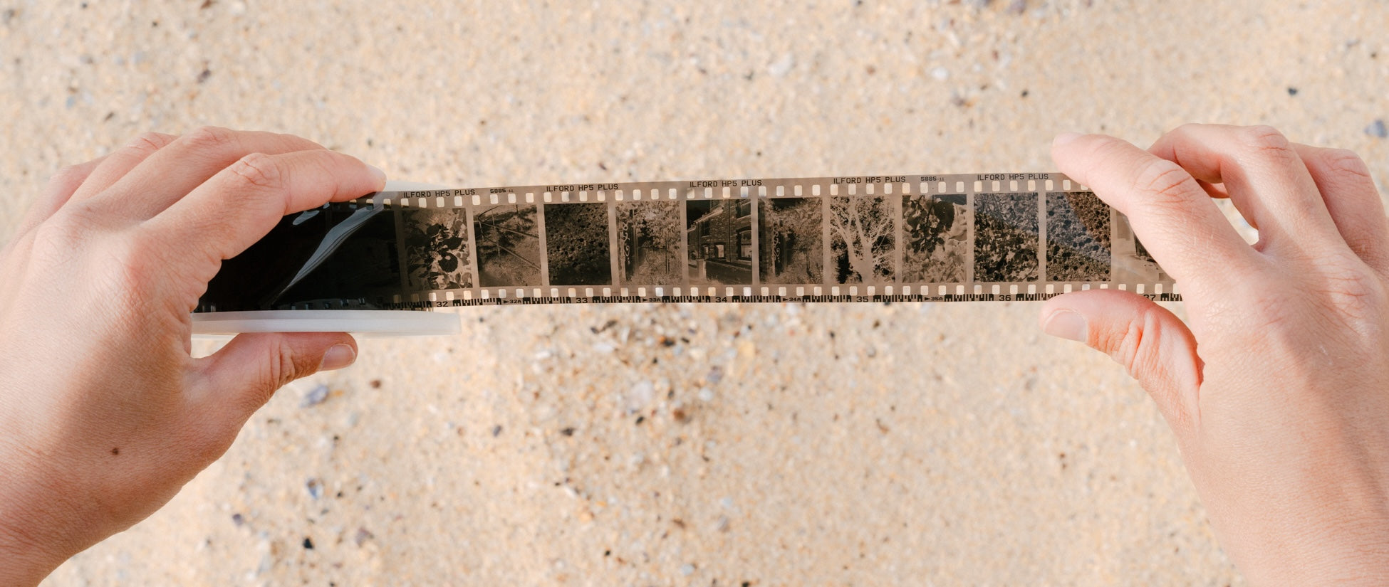 An analogue film strip held up against sand