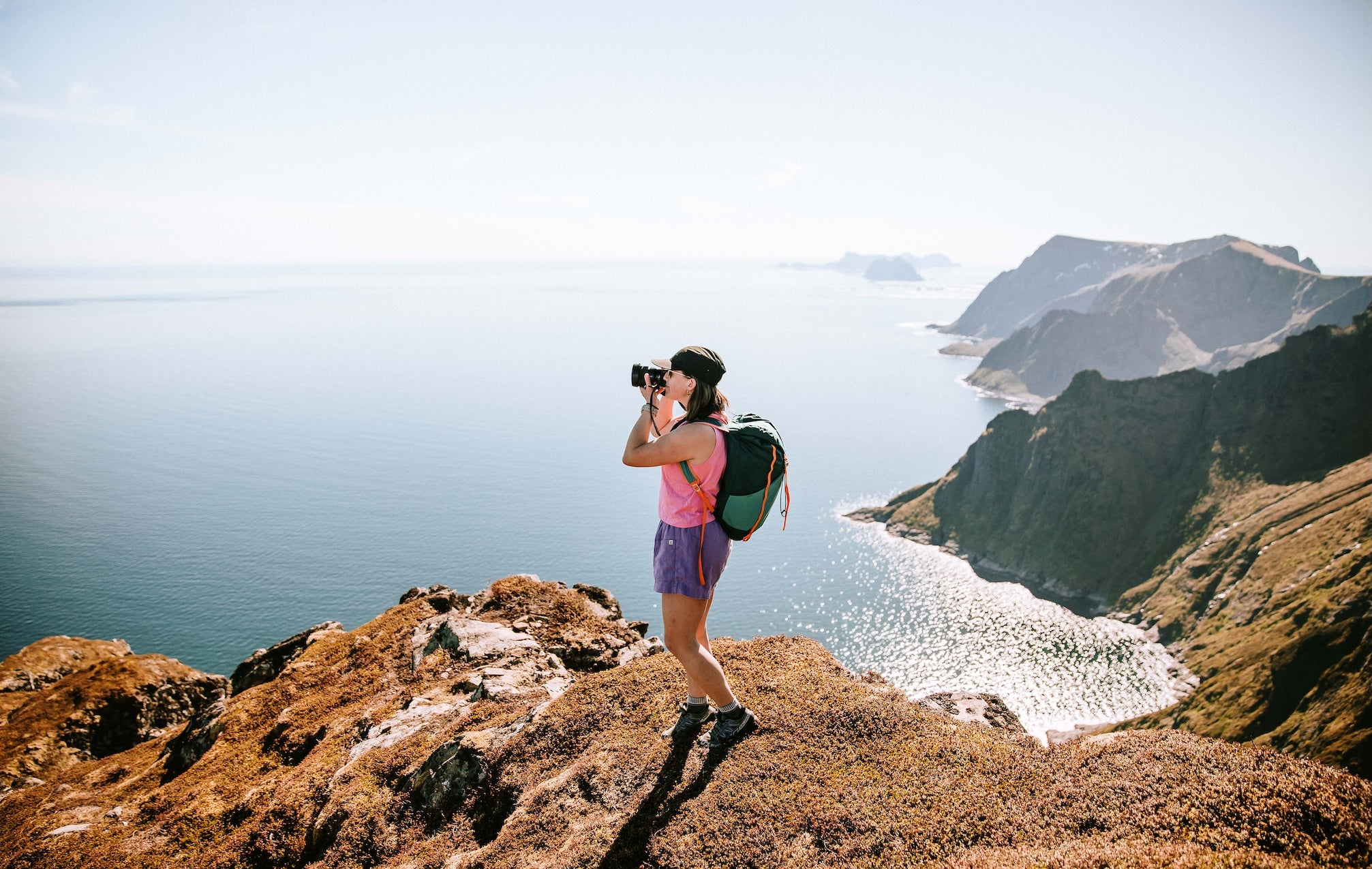 Person taking a photo of a scenic view from a high vantage point.