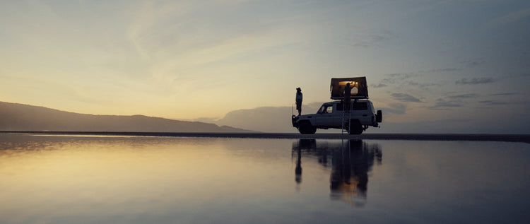 A sunset shot of an overlander vehicle with a roof tent