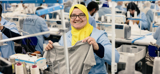A woman in the Morocco factory holds up a Passenger t-shirt