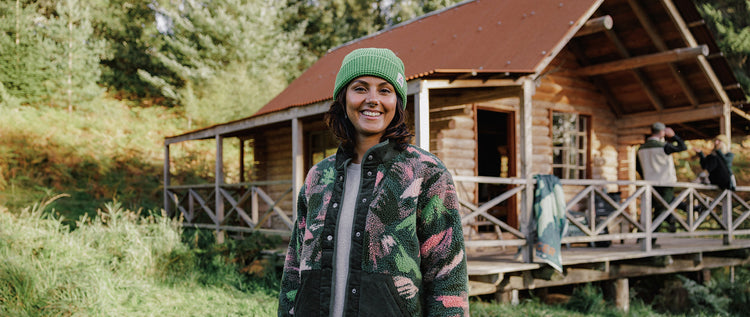 A woman stood in front of a woodland cabin